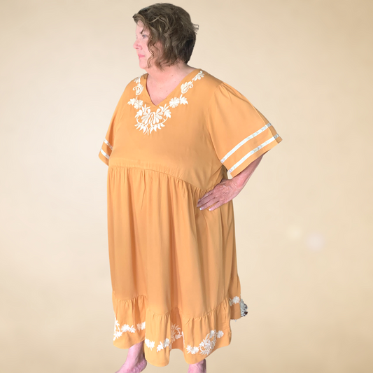 golden wheat dress with cream embroidered detail at neck line and hemline v neckline with ruffled hemline with banded detail on sleeves