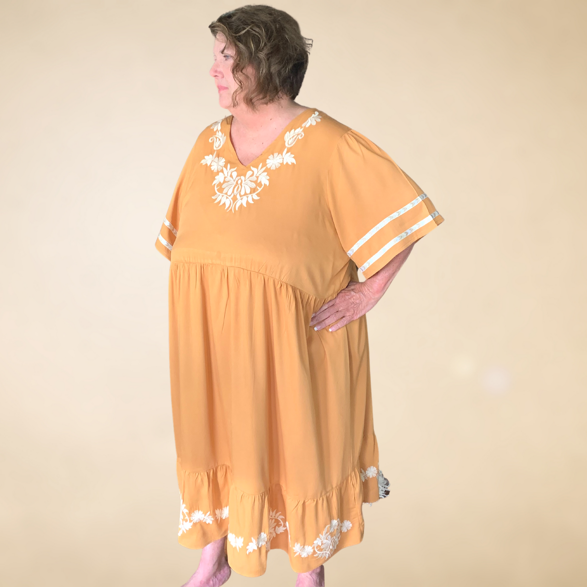 golden wheat dress with cream embroidered detail at neck line and hemline v neckline with ruffled hemline with banded detail on sleeves 